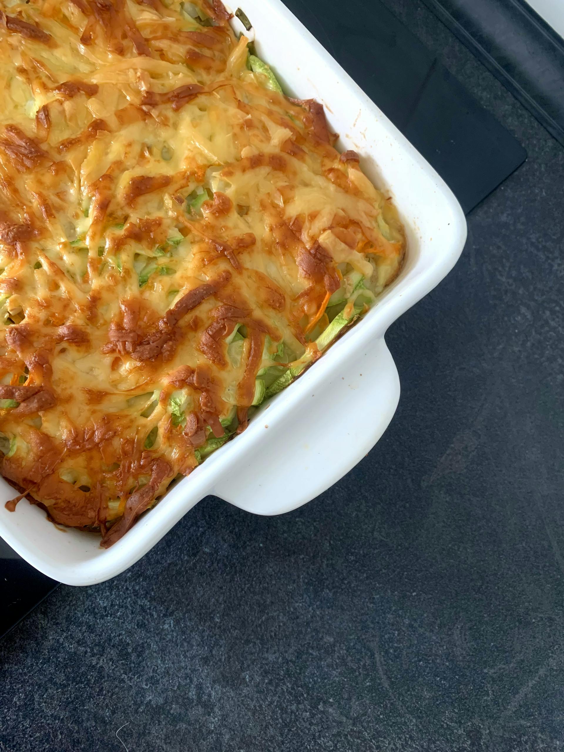A delicious homemade cheesy vegetable casserole fresh out of the oven in a white baking dish.