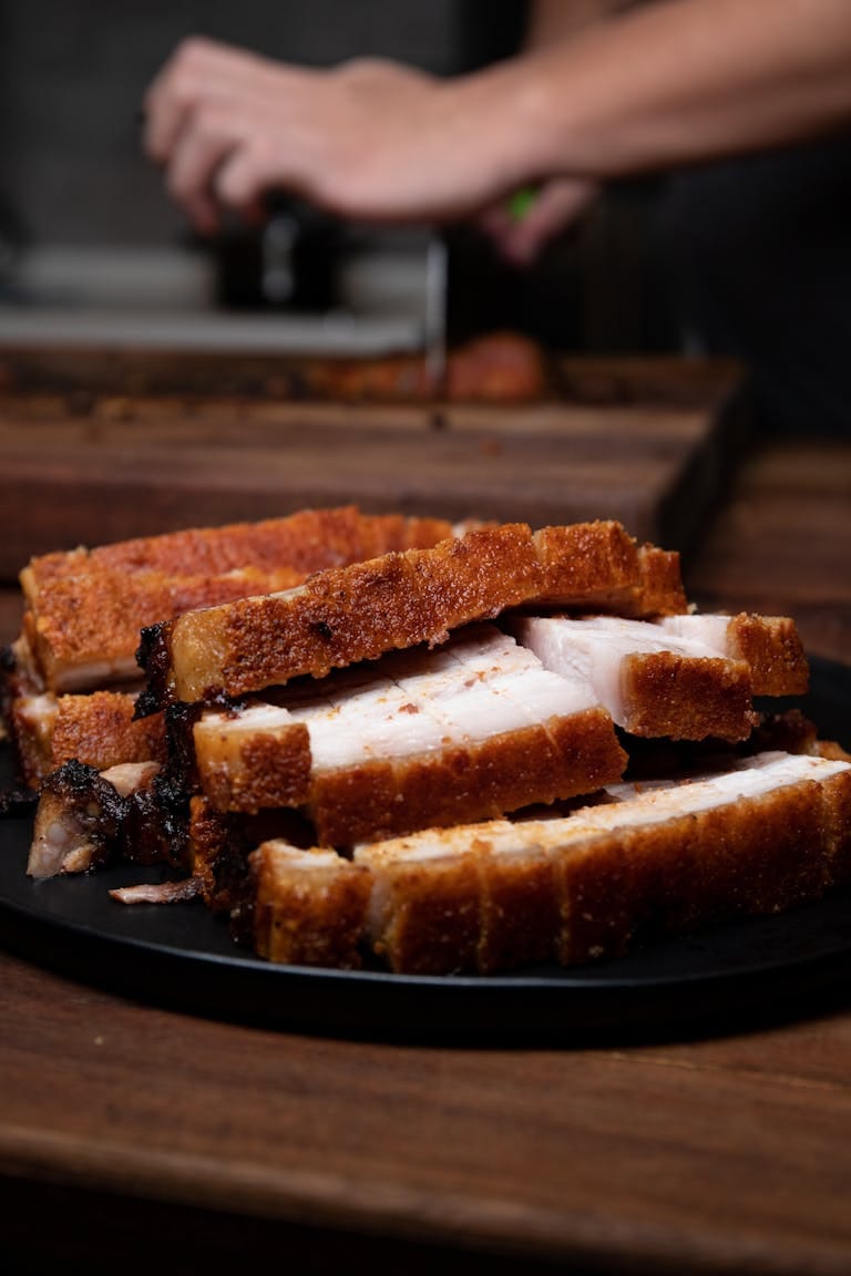 Delicious crispy roasted pork belly slices on a plate, a perfect tasty meal.