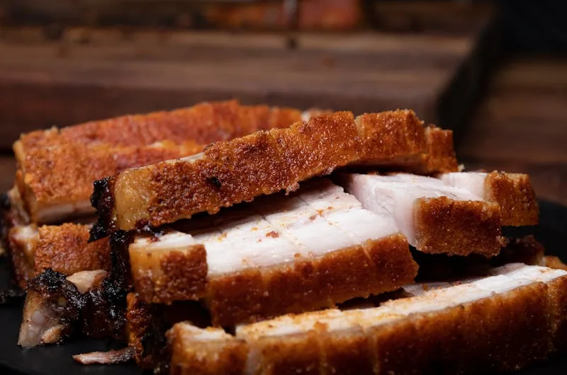 Delicious crispy roasted pork belly slices on a plate, a perfect tasty meal.